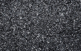 Close-up of black crumb rubber surface, illustrating material used in asphalt mixes for improved durability and high-temperature performance.