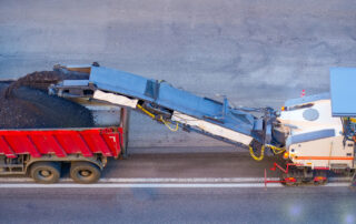 Recycled asphalt production: milling machine cutting worn pavement and transferring RAP into haul truck