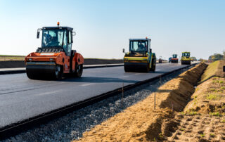 Fresh asphalt being placed and compacted during road construction, representing how asphalt softeners improve workability, compaction, and mix uniformity in asphalt paving.