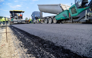 Construction scene showing heavy machinery and asphalt paving on a new road surface, highlighting asphalt mix installation where asphalt rejuvenator and bitumen softener decisions impact performance.