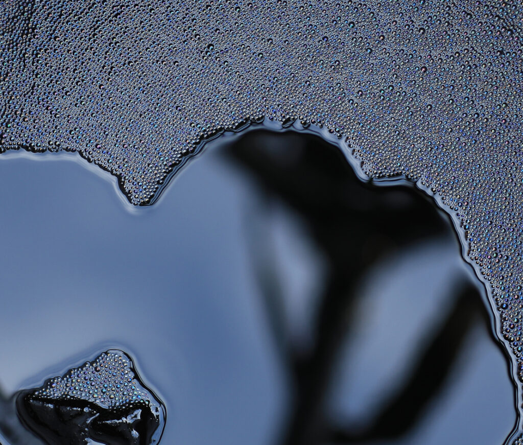 abstract black background of liquid asphalt bitumen Abstract close-up of black liquid bitumen surface with glossy, flowing texture, representing asphalt emulsions before breaking and curing in pavement applications.