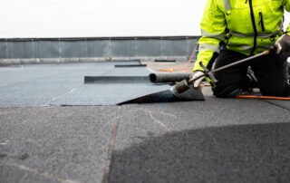 Professional roofer applying roofing membranes and materials for a commercial building