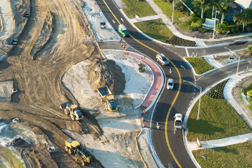 Roundabout construction roadworks on American transport infrastructure. Renovation of highway road with moving traffic. Development of interstate transportation concept Roadway construction underway to create more robust transportation networks relies on the use of asphalt additives to ensure long-lasting, durable, sustainable infrastructure.
