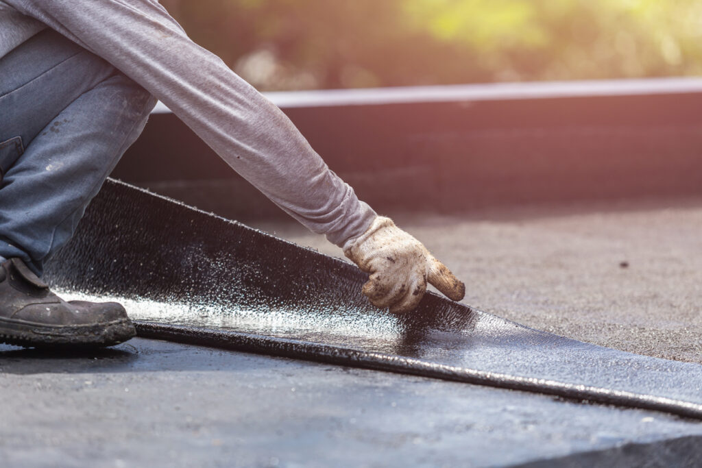 Application of asphalt waterproofing membrane during roof construction.