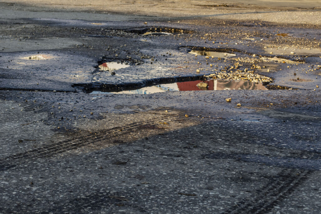 Pits on the road. Close-up photograph of a part of the road, asphalt on which there are many pits in which rainwater is poured Sripath asphalt additives help address deformations and damage to roadway surfaces.