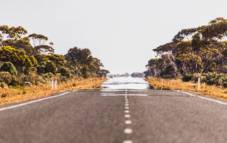 Heat refracting off a desert road creating a mirage, illustrating high-temperature asphalt conditions and extreme heat effects on roadway surfaces.