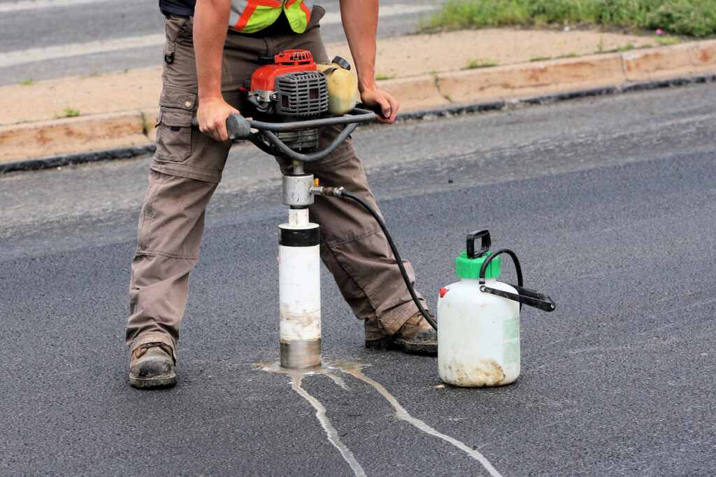Taking A Sample Technician taking a core sample from asphalt pavement for testing and quality control in road construction and asphalt mix evaluation.