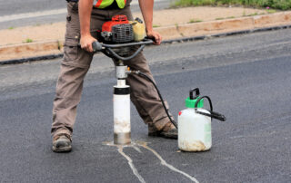 Technician taking a core sample from asphalt pavement for testing and quality control in road construction and asphalt mix evaluation.