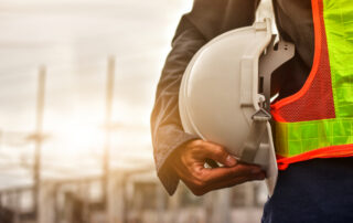 Construction worker holding a white safety hard hat, representing worker safety and the importance of construction professionals to infrastructure development.